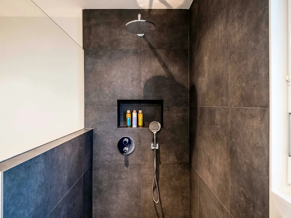 Walk-in shower with large-format dark tiles and a matte black mixer