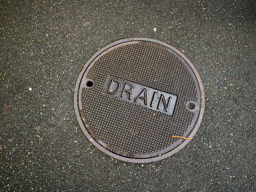Round cast-iron drain cover set in the ground