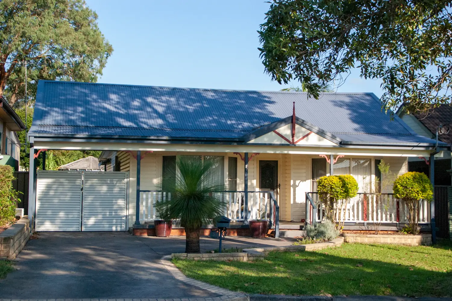 A finished weatherboard family home with a front verandah, lawn and driveway