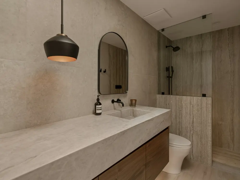 Bathroom in warm travertine-look stone with a long stone vanity
